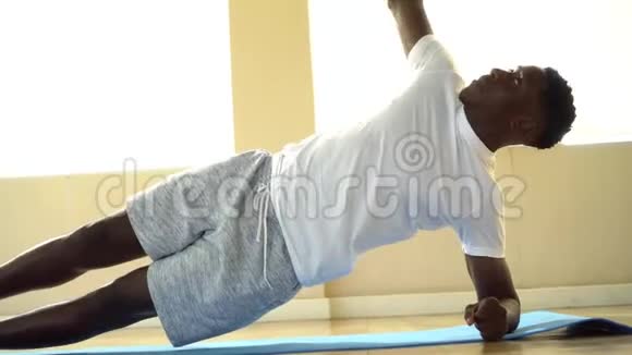 非裔美国运动员在健身房垫子上做侧板运动时单臂平衡视频的预览图