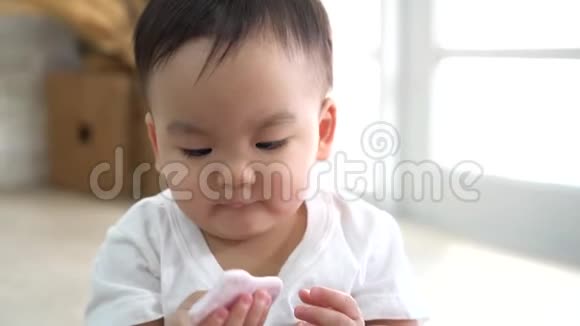 可爱的亚洲婴儿咬零食而坐在地板上舒适的房间在家里视频的预览图