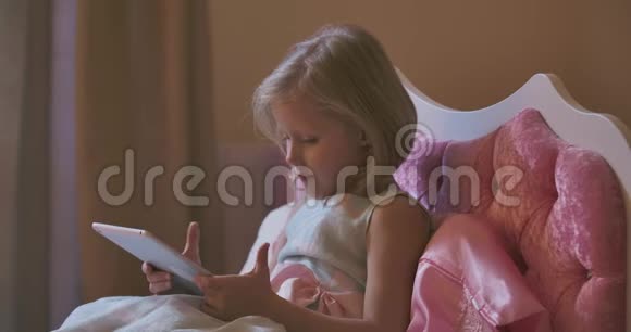 白人女孩躺在平板电脑旁睡觉漂亮的孩子在粉红色的床上睡着了在家休息视频的预览图