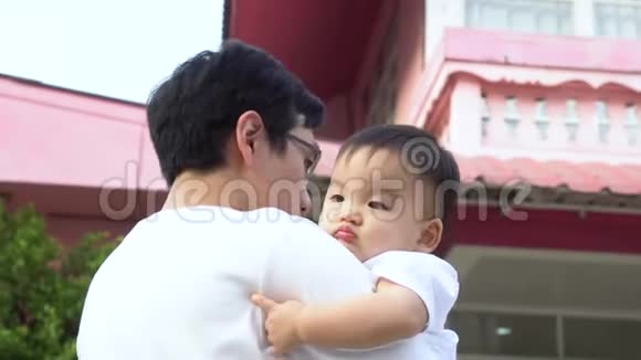爱的父亲举起快乐的亚洲婴儿和孩子一起玩耍站在他们的房子前面视频的预览图