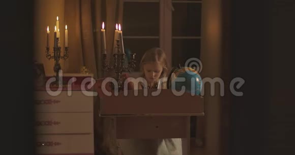 在烛光下穿过白人女学生在家做作业的门口坐在书桌前的金发孩子视频的预览图