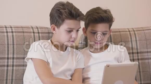 白种人双胞胎兄弟在平板电脑上玩电子游戏和击掌的特写镜头小兄弟玩得开心视频的预览图