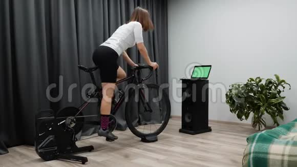 室内虚拟自行车适合骑自行车的女人骑自行车在家里的固定自行车从马鞍上出来单车概念视频的预览图