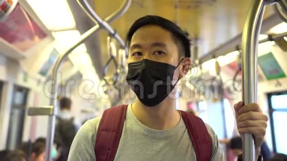 在地铁列车上一名戴着黑色手术面罩的亚洲年轻人在新型冠状病毒Covid19号列车上关门视频的预览图