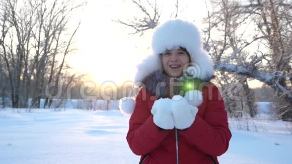 快乐的孩子一个女孩在雪地里吹着手掌雪飞了起来闪闪发光雪在阳光下落下闪闪发光儿童视频的预览图