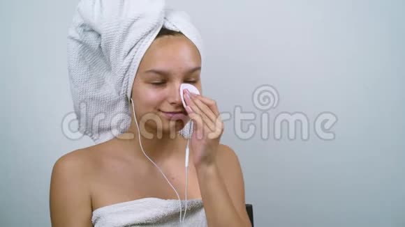 十几岁的孩子在浴巾里听音乐把多余的奶油从脸上去掉视频的预览图