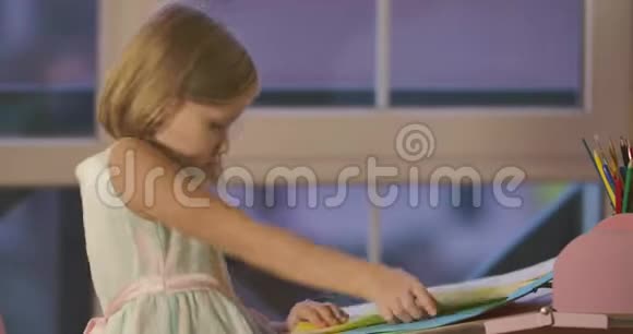 可爱的高加索女学生晚上在家做作业穿着漂亮裙子的金发女孩坐在桌子旁视频的预览图
