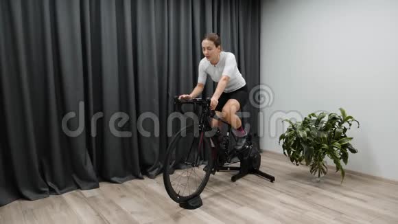 室内智能教练骑自行车的女人在骑自行车时喝水或等渗饮料专业自行车训练计划视频的预览图