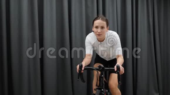可爱的女性在室内循环训练心脏自行车家庭教练作为健身锻炼的一部分单车概念视频的预览图