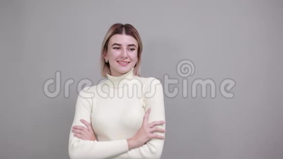 幸福的年轻女子穿着便装双手交叉隔在灰色的墙上视频的预览图