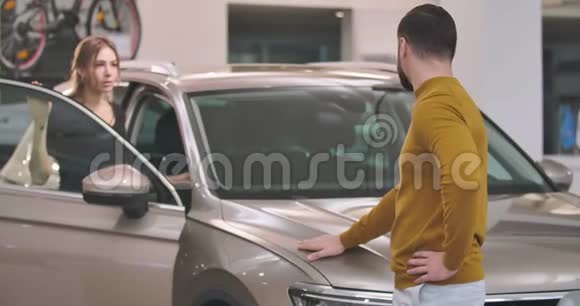 美丽的高加索家庭站在汽车经销商和审查新汽车自信的男人和女人视频的预览图