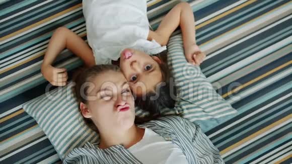 母亲和女儿在公寓的地板上做滑稽的脸的俯视图视频的预览图