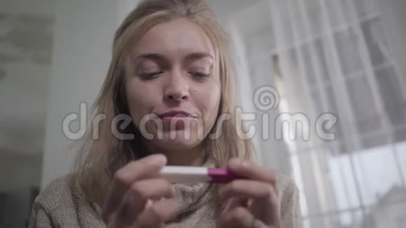美丽的白种人女孩的特写脸棕色的眼睛抱着怀孕测试微笑快乐的年轻女人视频的预览图
