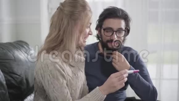 年轻的金发白种人妇女展示她的男朋友或丈夫肯定怀孕测试有胡子的人模仿快乐视频的预览图