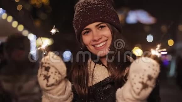 穿上冬天的衣服穿上漂亮的微笑女孩高兴地看着相机拿着火花站在坠落中的女人视频的预览图