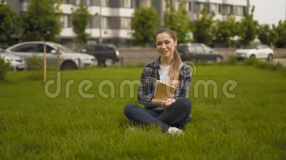 很长一段时间20岁的女孩穿着格子衬衫坐在草地上真诚地笑了视频的预览图