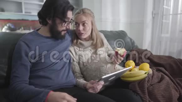 快乐的高加索家庭使用社交媒体和交谈年轻人和怀孕的妻子在家休息快乐的一对视频的预览图