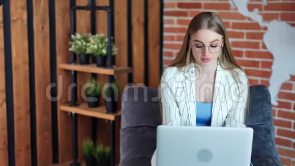 可爱的年轻休闲女商人在现代阁楼办公室工作笔记本电脑中镜头视频的预览图