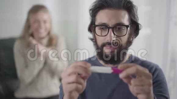 高加索男人的近照脸拿着孕检回头看他金发的妻子拍手微笑着视频的预览图