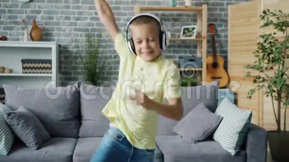 快乐男孩在家玩的肖像用耳机听音乐跳舞视频的预览图