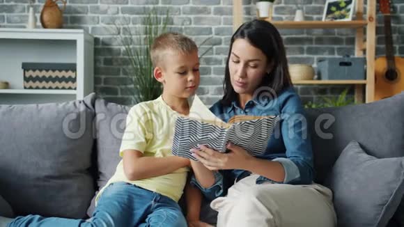 一位年轻的女士在室内给一个可爱的男孩读童话故事视频的预览图