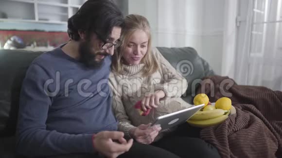 开朗的已婚夫妇看着平板电脑大声笑了出来一名白人孕妇展示她的丈夫视频的预览图