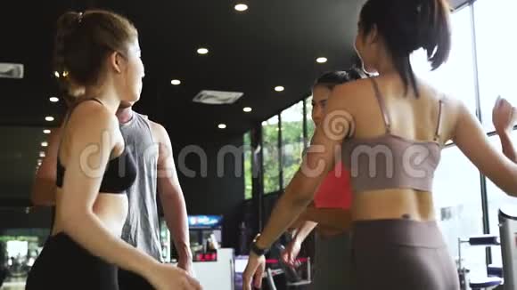 微笑的男人和女人一起在健身馆牵手一群年轻人在健身房做高五个手势视频的预览图