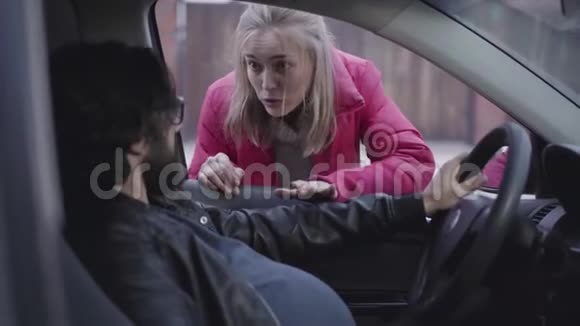 担心的白种人女人通过侧车窗和她怀孕的丈夫说话有趣的男性期待坐在司机视频的预览图