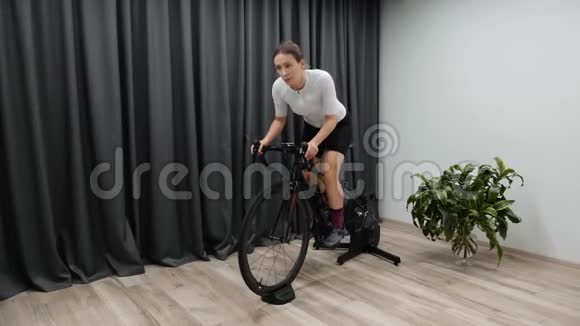 在家里骑着固定的自行车教练在室内骑脚踏车作为比赛准备的一部分职业自行车视频的预览图