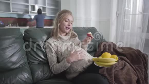 漂亮怀孕的白人女孩吃苹果抚摸她的腹部的肖像她丈夫在找什么视频的预览图
