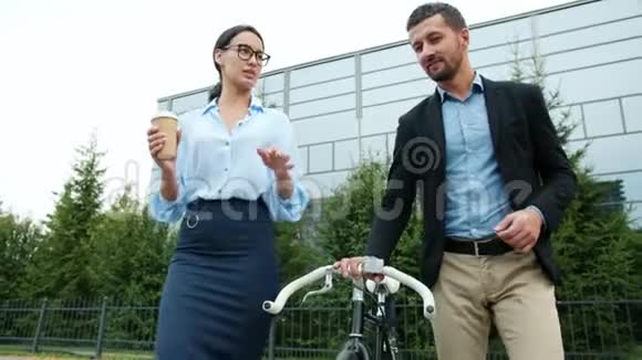 男人和女人的同事骑着自行车从工作中走出来喝着咖啡说话视频的预览图