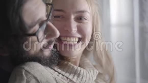 一对快乐的白种人夫妇的特写脸在说话和微笑积极的漂亮女人和留着胡子的年轻男人视频的预览图