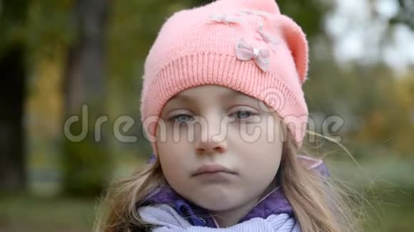 一个5岁的悲伤女孩在城市秋公园背景下的肖像视频的预览图