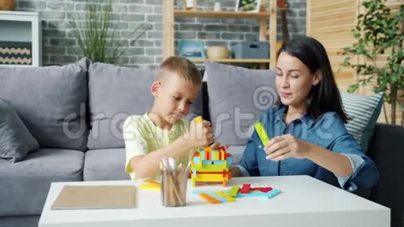 年轻女士在家里用积木和快乐的孩子玩耍的慢动作视频的预览图