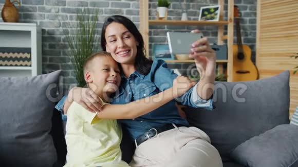 爱妈妈和可爱的儿子一起自拍用智能手机摄像头拥抱孩子视频的预览图
