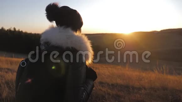 日落时带背包的女旅行者在山上徒步旅行剪影徒步旅行自由和幸福的概念视频的预览图