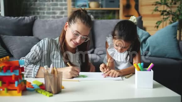 可爱的小女孩有创造力的孩子一边画画一边妈妈帮助表达爱视频的预览图