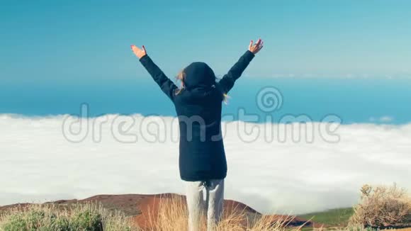 自由旅女站在特内里费的山顶上举起双臂欣赏美丽的景色视频的预览图