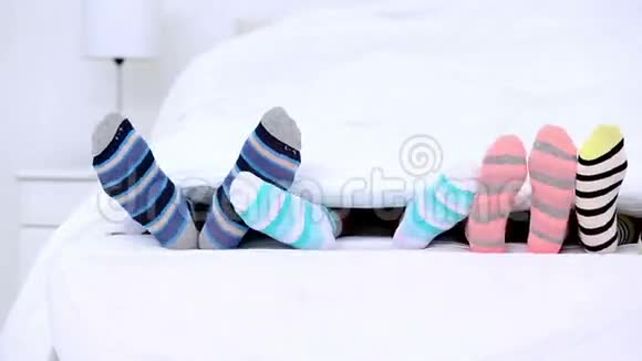 穿着条纹袜子踢在被子下面的家人的脚视频的预览图