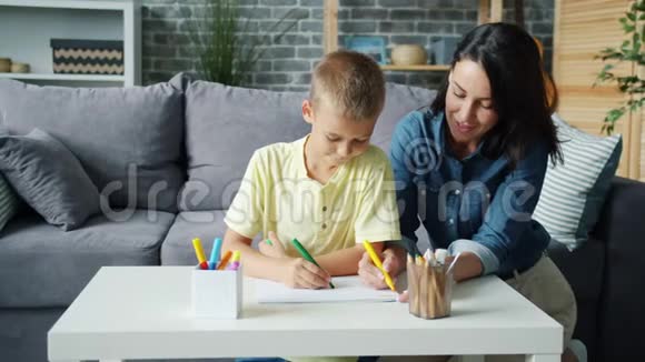小男孩在家舒适的房间里和有爱心的妈妈一起画记号视频的预览图