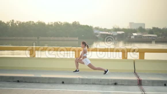 运动员女人在海滩路跑之前热身亚洲女跑运动员夏季耐力训练视频的预览图