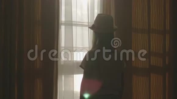 小女孩打开窗帘透过窗户看视频的预览图