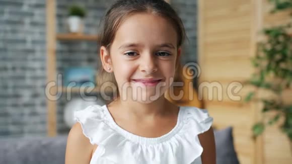 一个人在家里对着镜头微笑的漂亮可爱的小女孩的肖像视频的预览图