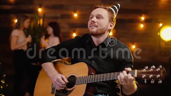 快乐的年轻人在新年装饰的背景下弹吉他视频的预览图