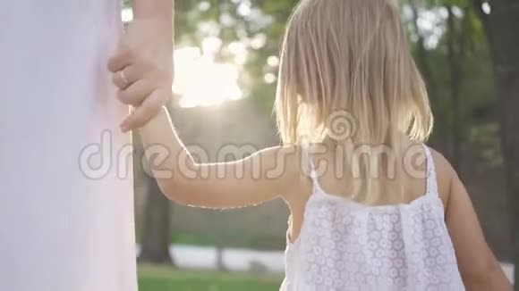 小金发女孩走着牵着大人的手孩子们在公园里消磨时间公园或森林里的晴天视频的预览图