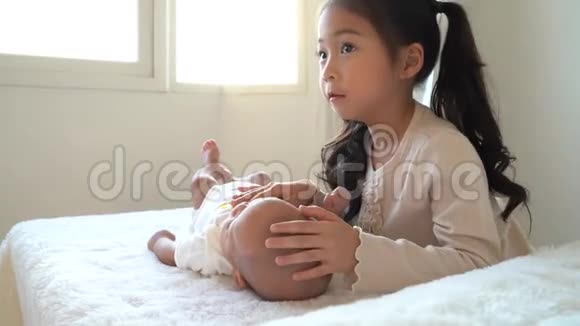 亚洲一家可爱的小妹妹在床上抚摸着刚出生的小男孩弟弟视频的预览图