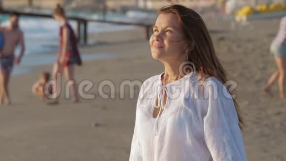 一个年轻的女人微笑放松享受沙滩上的生活视频的预览图