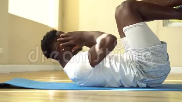 年轻的非裔美国人在健身房的瑜伽垫上做仰卧起坐运动男性健身模特在健身过程中表现出紧张视频的预览图