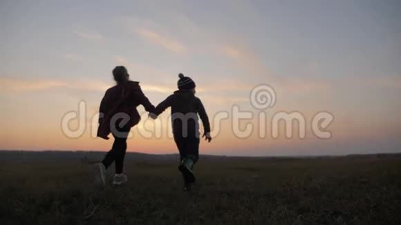 日落时分两个孩子在草地上奔跑童年梦想的概念或前进的愿望视频的预览图