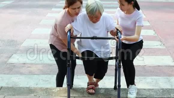 亚洲的母亲和女儿帮助照顾支持户外的老奶奶过马路后障碍从人行道人行道是高大的视频的预览图